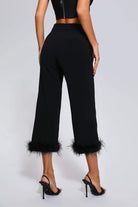 Elegante schwarze Hose mit Federbesatz am Saum, kombiniert mit High Heels. Perfekt für stilvolle Abendmode und modische Outfits.