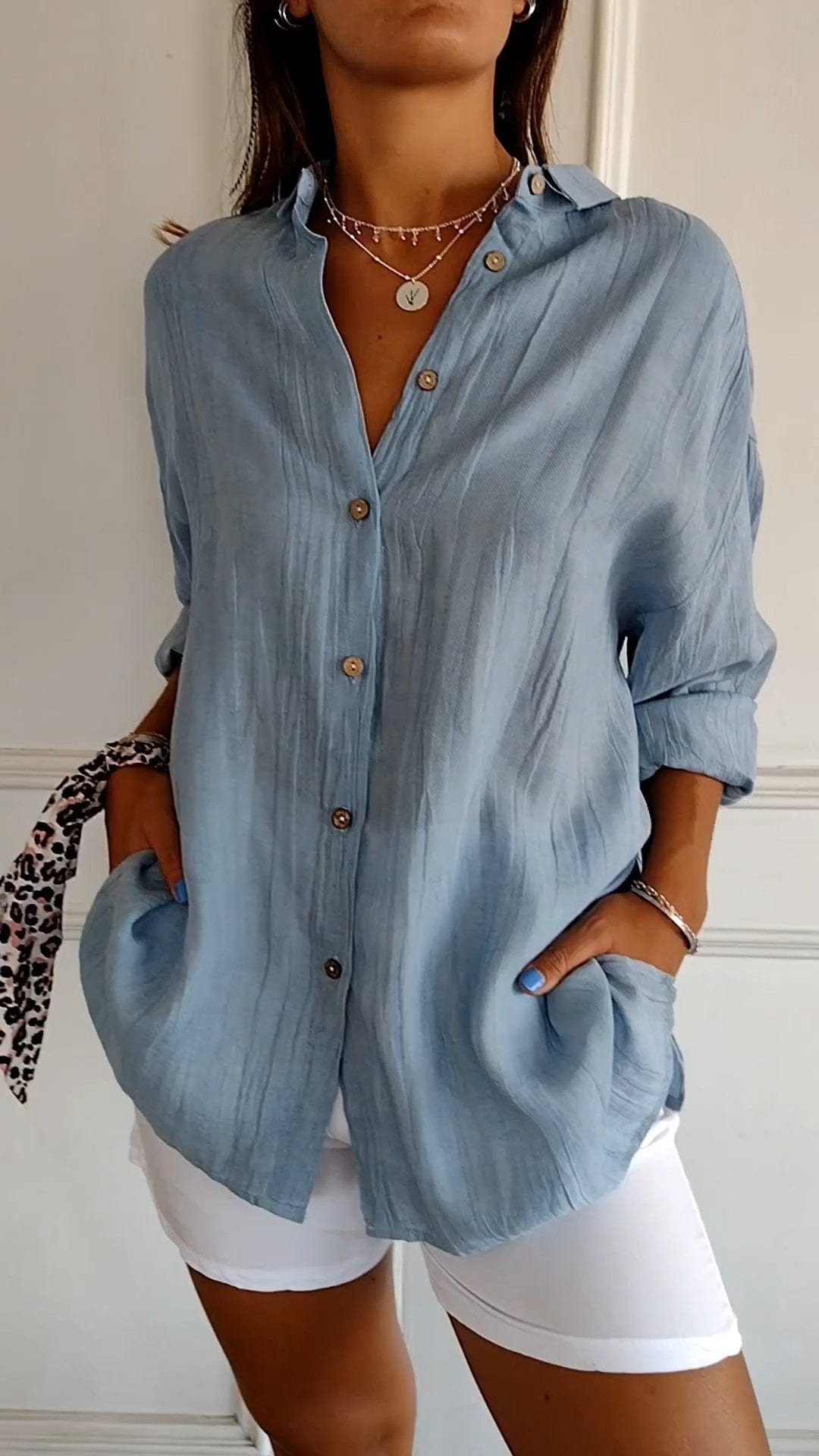 Damenmode: Elegante, hellblaue Bluse mit Knopfleiste und langen Ärmeln, kombiniert mit weißen Shorts. Perfekt für Sommer und Freizeit.