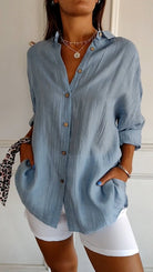 Damenmode: Elegante, hellblaue Bluse mit Knopfleiste und langen Ärmeln, kombiniert mit weißen Shorts. Perfekt für Sommer und Freizeit.