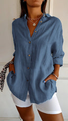 Frau in blauer Leinenbluse, lässig, mit Knöpfen, modisch, Sommermode, weiße Hose.
