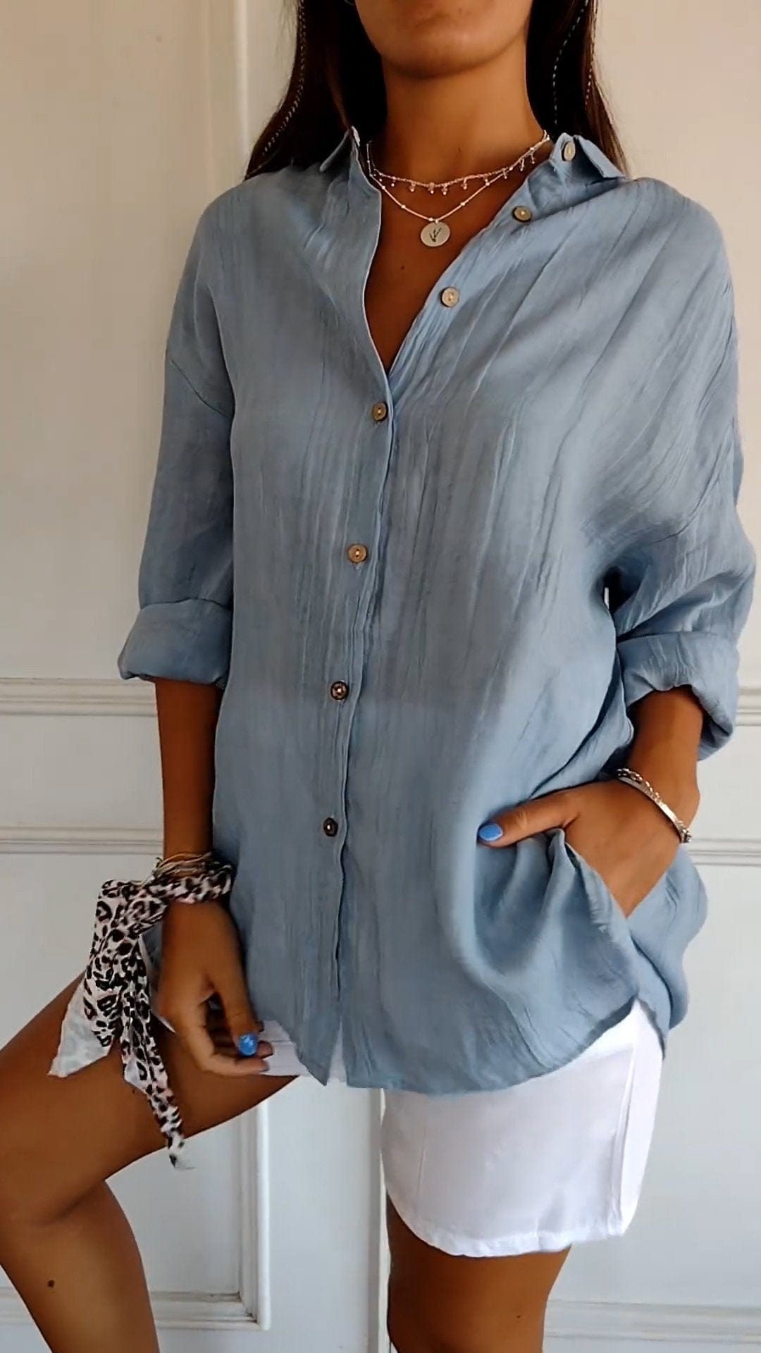 Damenmode: Lockeres, hellblaues Leinenhemd mit Knopfleiste, kombiniert mit weißen Shorts. Perfekt für Sommer, Freizeit und Strand.