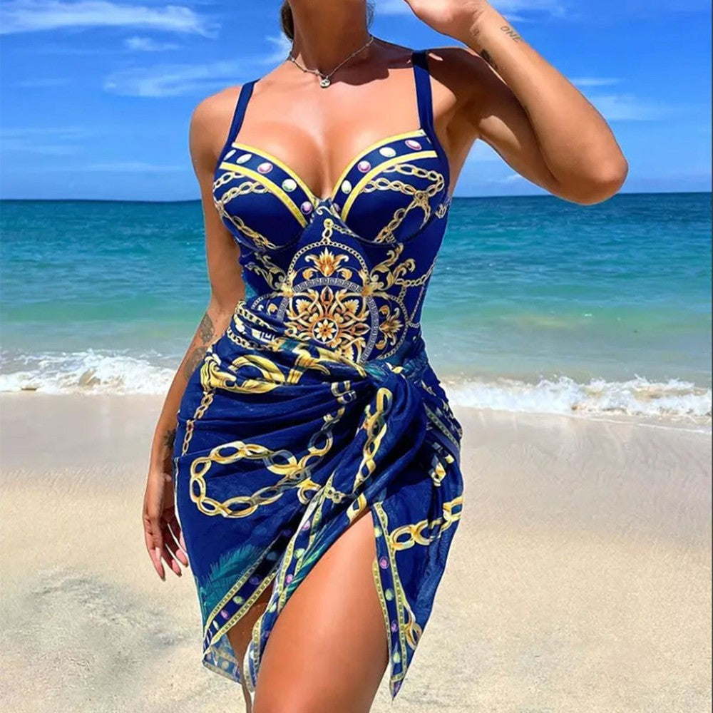 Eleganter blauer Badeanzug mit goldenen Kettenmustern am Strand, ideal für Sommermode und Strandurlaub. Perfekt für stilvolle Strandauftritte.