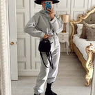 Grauer Trainingsanzug mit kurzem Sweatshirt, kombiniert mit schwarzem Hut und Tasche. Perfekt für lässige Mode und Streetwear-Trends.