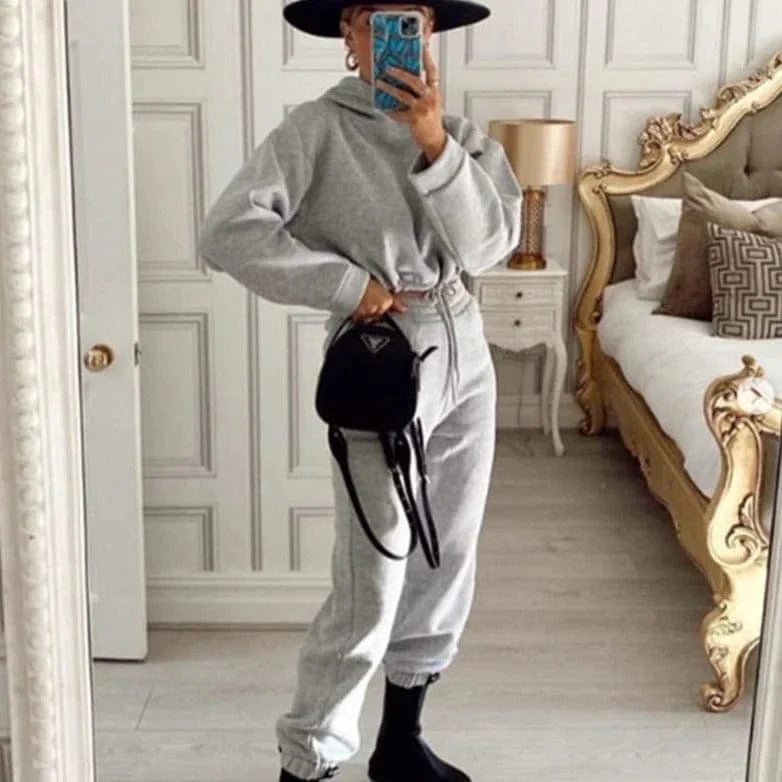 Grauer Trainingsanzug mit kurzem Sweatshirt, kombiniert mit schwarzem Hut und Tasche. Perfekt für lässige Mode und Streetwear-Trends.