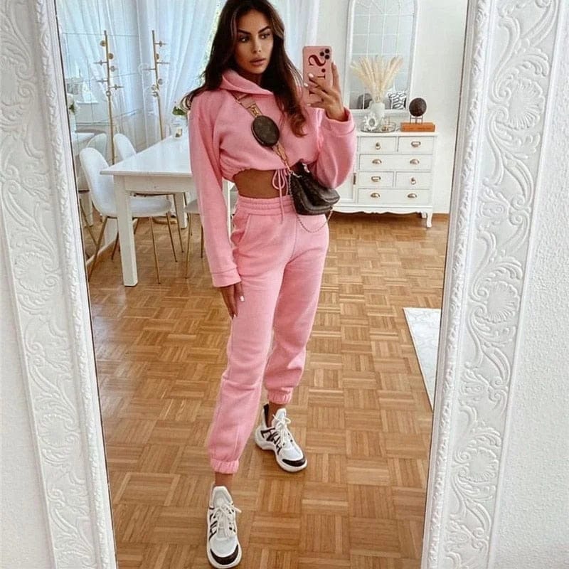 Frau in rosa Trainingsanzug mit kurzem Sweatshirt, modisch und bequem, ideal für Freizeit und Sport. Perfekt für trendige Streetwear-Looks.