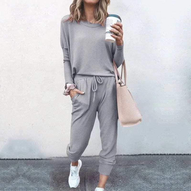 Graues Sweatshirt-Set für Damen, lässig und bequem, ideal für Freizeit und Sport. Perfekt kombiniert mit Sneakers und Handtasche.