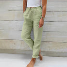 Frau in hellgrüner Leinenhose, weißem Top, lässiger Look, Sommermode, Holz-Hintergrund.