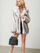 Damenmode: Eleganter Kunstpelzmantel in Grau-Weiß, kombiniert mit schwarzer Handtasche. Perfekt für stilvolle Winteroutfits und Trends.