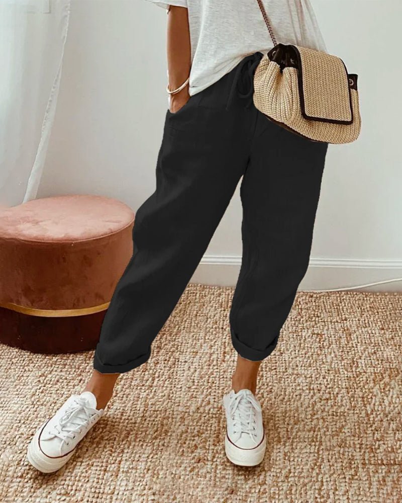 Damen Leinenhose schwarz, lässig, atmungsaktiv, ideal für Sommer, kombiniert mit weißen Sneakers.