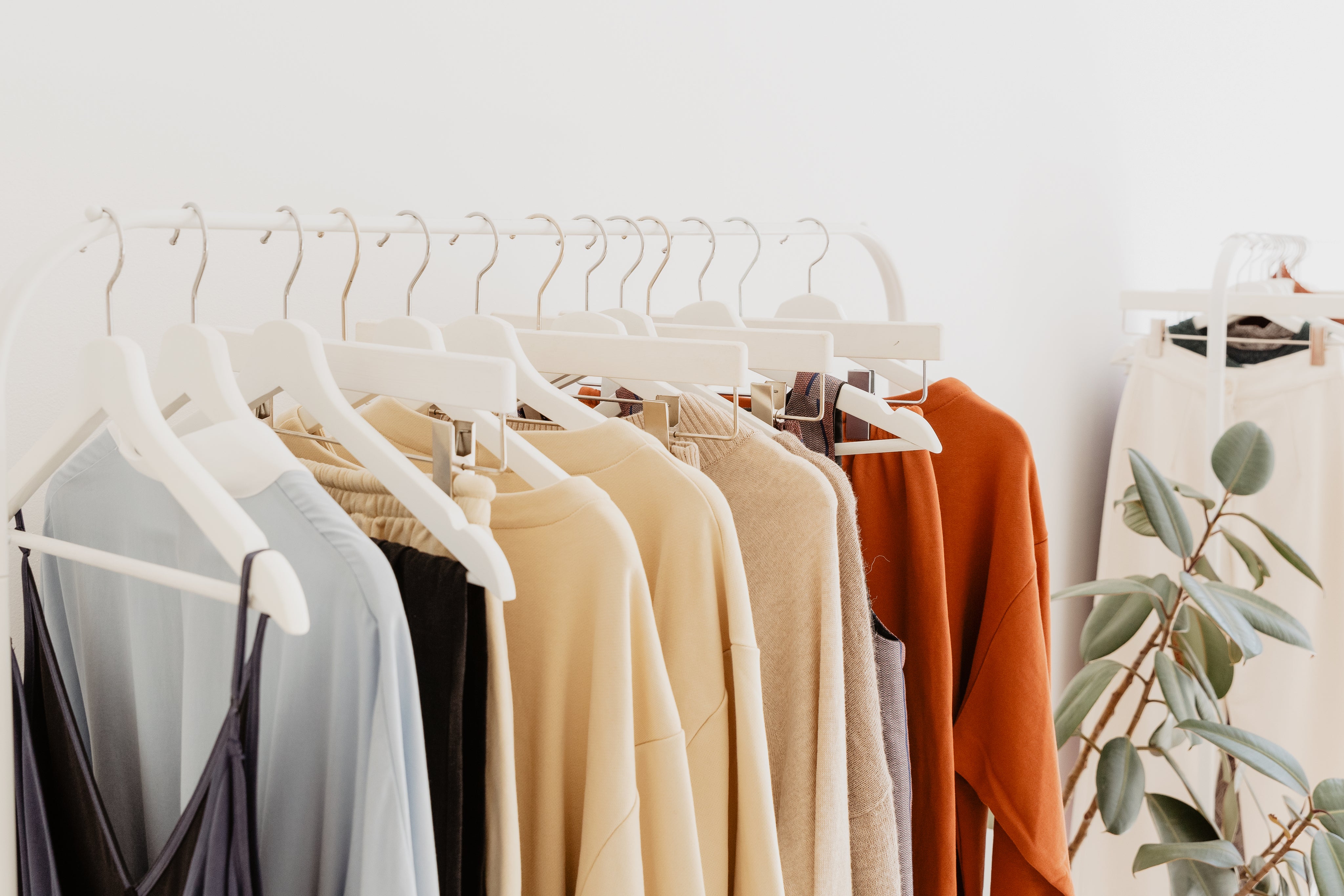 Minimalistische Kleiderstange mit eleganter Damenmode in neutralen Tönen, ideal für stilvolle Einzelhandelspräsentationen und Boutique-Dekor.