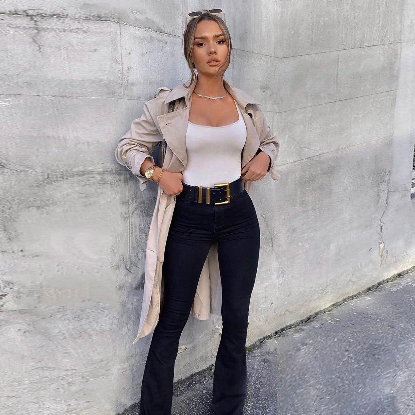 Frau in schwarzer Jeans und beigem Trenchcoat, modisch, urbaner Stil, Streetwear, elegante Kleidung, trendige Damenmode, lässiger Look.