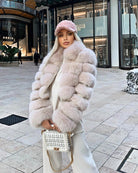 Damen in luxuriösem, kurzem Fuchspelzmantel, kombiniert mit modischer Mütze und eleganter Handtasche, ideal für stilvolle Wintermode.