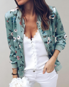 Damenblouson mit floralem Muster in Grün, kombiniert mit weißem Top und Hose. Modetrend, Frühlingsjacke, stilvolle Damenmode, lässiger Look.