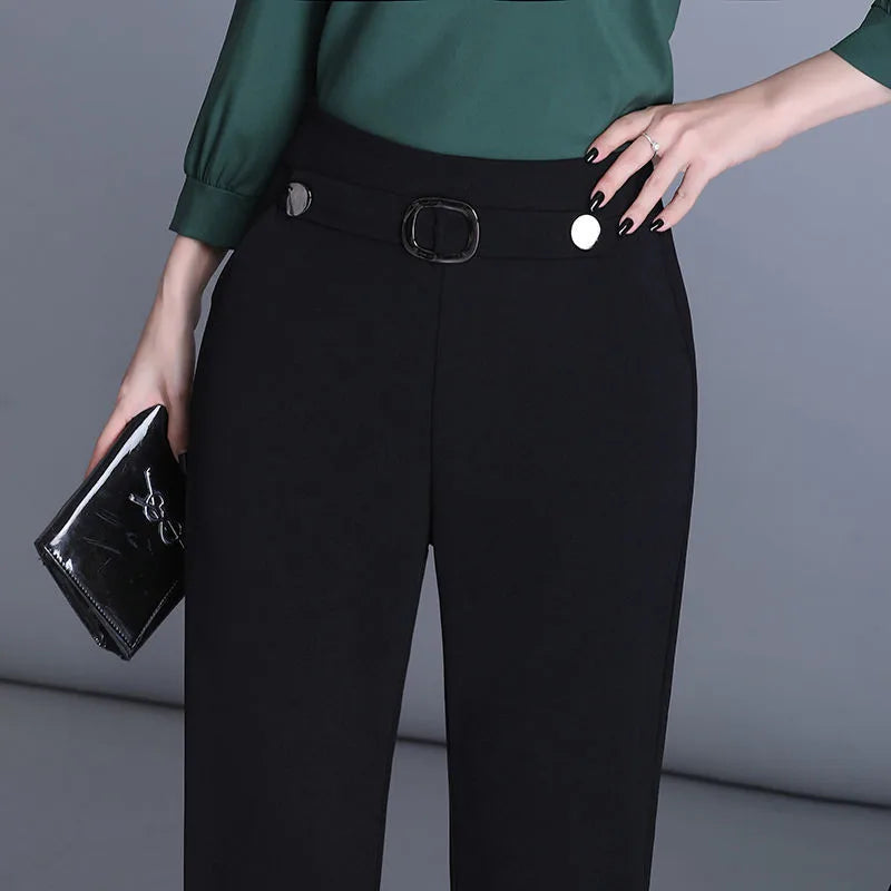 Elegante Damenhose in Schwarz mit Gürtel und silbernen Knöpfen, kombiniert mit grüner Bluse und schwarzer Clutch. Perfekt für Business-Looks.