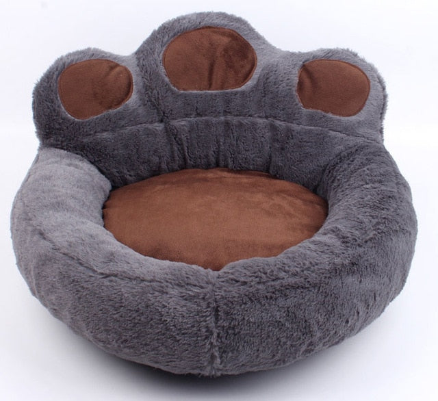 Graues, plüschiges Hundebett in Pfotenform, braune Details, gemütlich, waschbar.
