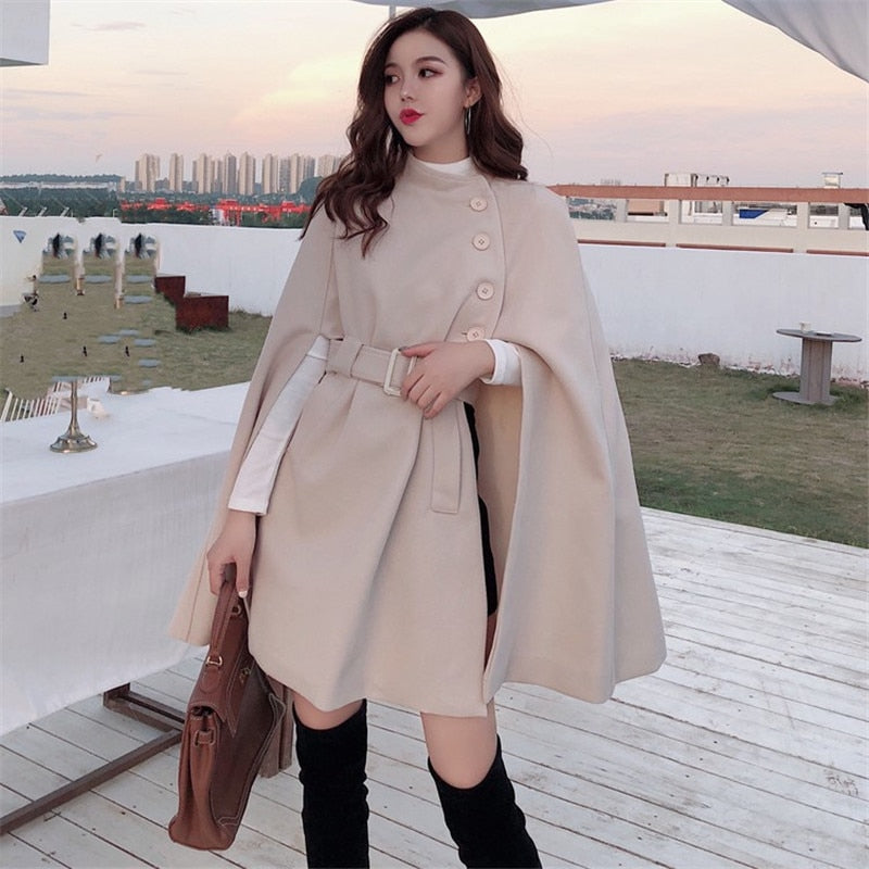 Eleganter Damenmantel in Beige mit Gürtel und Knöpfen, ideal für Herbstmode. Stilvoller Umhang-Look, perfekt für urbane Outfits.