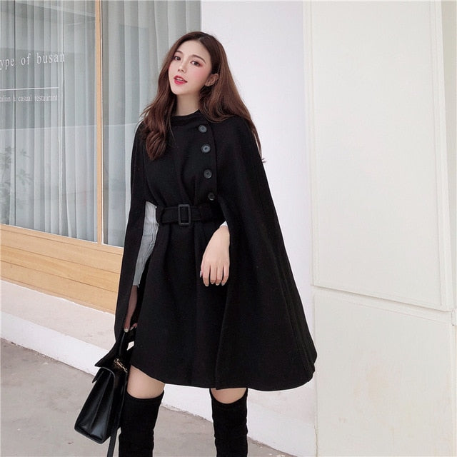 Elegantes schwarzes Cape-Kleid für Damen, ideal für Herbstmode. Stilvoller Look mit Knopfleiste und Gürtel, perfekt für trendbewusste Outfits.