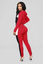 Roter Damen-Trainingsanzug mit Kapuze, schwarz-weißen Streifen, figurbetontem Design. Perfekt für Sport und Freizeit. Modisch und bequem.