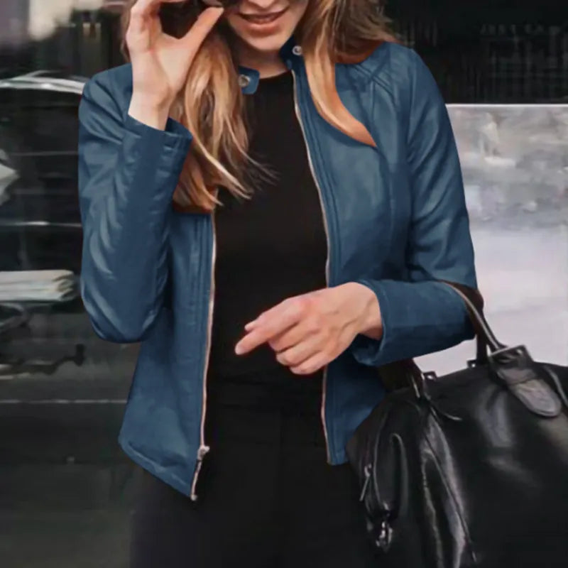 Frau in blauer Lederjacke, hält schwarze Handtasche. Modetrend, Damenbekleidung, stilvolle Jacke, Accessoires, urbane Mode.