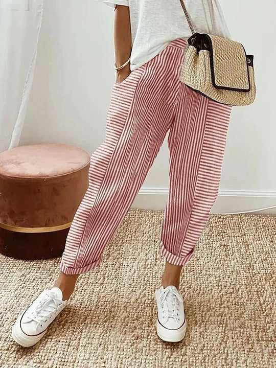 Gestreifte rote Hose für Damen, kombiniert mit weißem T-Shirt und Sneakers. Perfekt für lässige Sommermode und trendige Freizeitlooks.