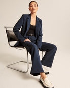 Frau im eleganten blauen Anzug sitzt auf einem modernen Stuhl. Businessmode, Damenanzug, stilvolle Bürooutfits, zeitlose Eleganz.