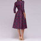 Elegantes, mittellanges Retro-Kleid mit roten Blumenmustern auf dunkelblauem Hintergrund, 3/4-Ärmeln und tailliertem Schnitt. Perfekt für Vintage-Looks.