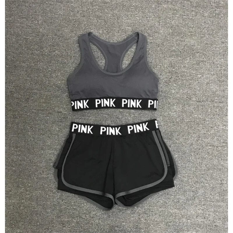 Graues Sportset für Damen mit "PINK" Schriftzug, bestehend aus Sport-BH und Shorts. Ideal für Fitness, Yoga und Laufen. Bequem und stylisch.