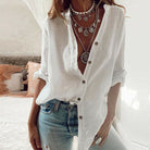 Weiße Leinenbluse Damen, lässig offen getragen, kombiniert mit Jeans und auffälligen Halsketten. Perfekt für Sommermode und Boho-Stil.