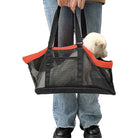 Person trägt schwarze Netz-Hundetasche mit rotem Rand, Hund im Inneren, Jeans und schwarze Schuhe.