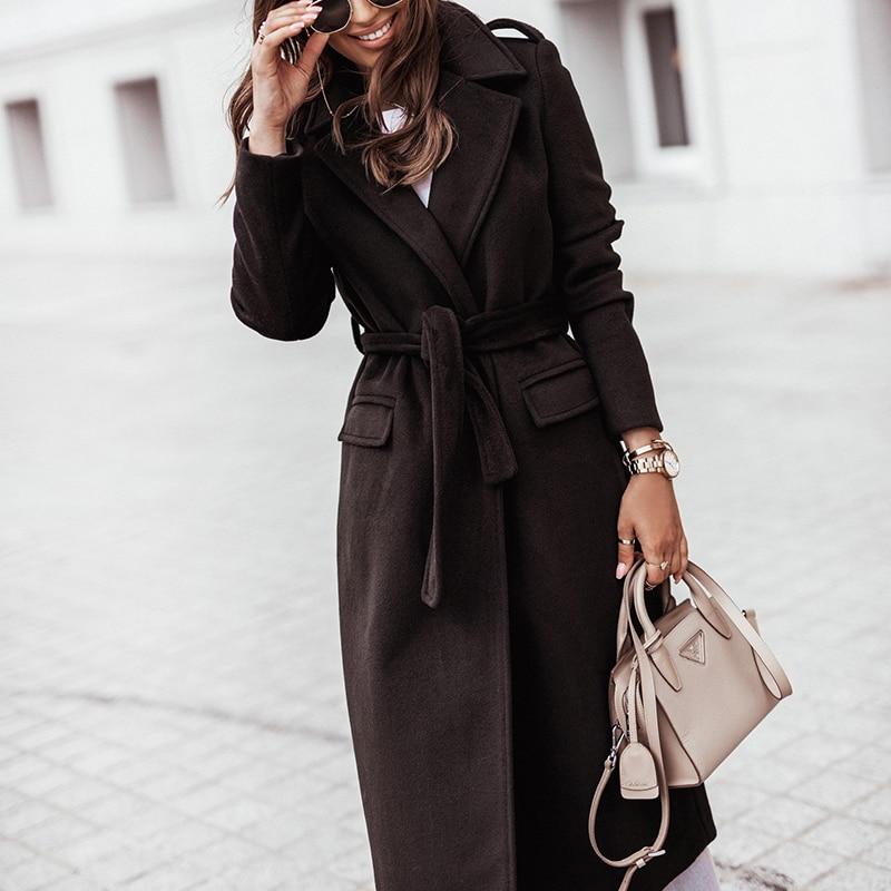 Eleganter schwarzer Wintermantel für Damen, stilvoll mit Gürtel, ideal für kalte Tage. Perfekt kombiniert mit modischer Handtasche.