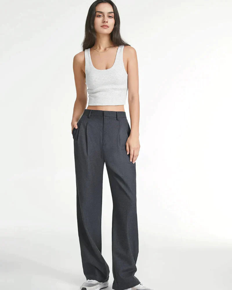 Frau in grauer, weiter Hose und weißem Tanktop. Modetrend, lässiger Stil, elegante Damenbekleidung, zeitloses Design, bequeme Passform.