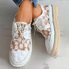 Stilvolle, luftige Damenschuhe mit Blumenmuster, ideal für den Sommer. Bequeme, modische Sneaker in Weiß mit floralen Details.