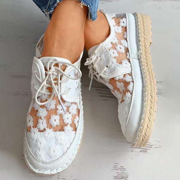 Stilvolle, luftige Damenschuhe mit Blumenmuster, ideal für den Sommer. Bequeme, modische Sneaker in Weiß mit floralen Details.