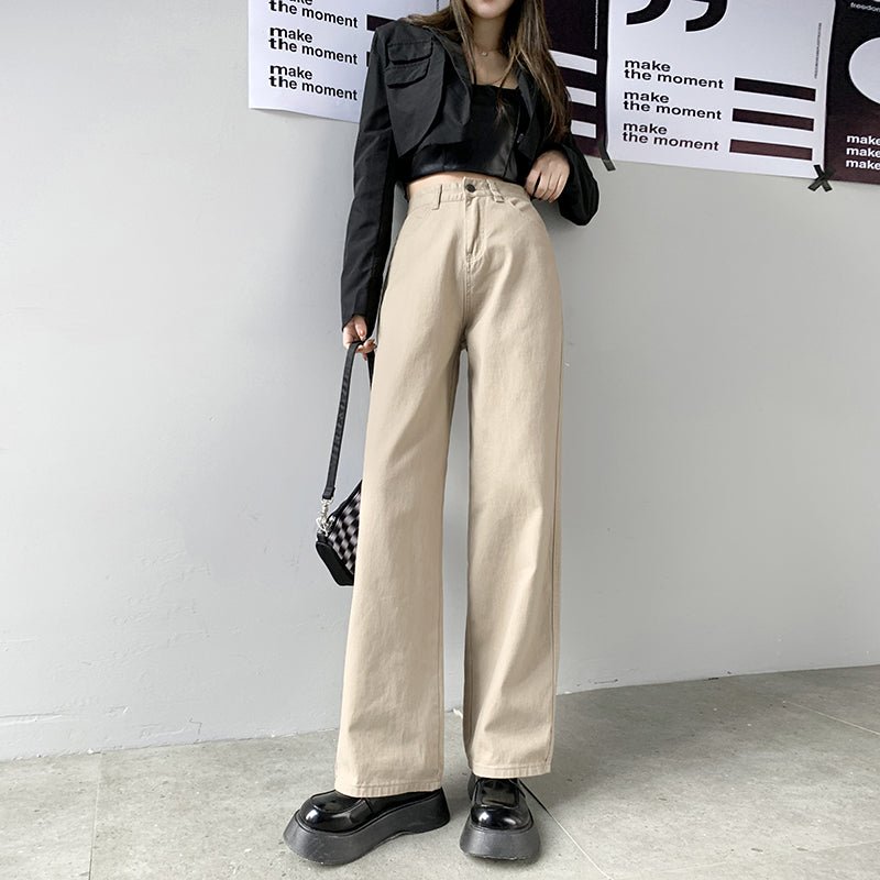 Damen-Jeans mit geradem Bein und hoher Taille in Beige, kombiniert mit schwarzer Jacke und Plateau-Schuhen. Modetrend, Streetstyle, lässig.