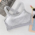 Grauer Sport-BH mit gekreuzten Trägern, ideal für Fitness und Yoga. Atmungsaktives Material, bequem und stilvoll für aktive Frauen.