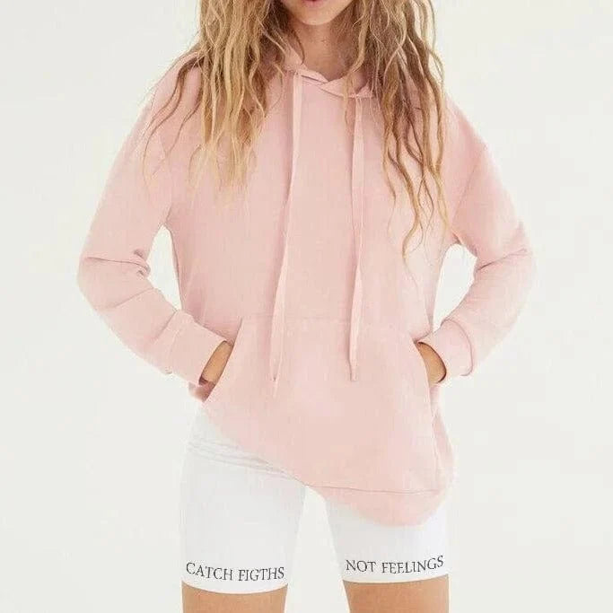 Damen-Sporthose weiß mit Aufschrift "Catch Fights Not Feelings", kombiniert mit rosa Hoodie. Trendige Fitnessmode, bequem und stylisch.