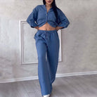 Frau in modischem blauen Denim-Set, bestehend aus Crop-Top und weiten Hosen. Trendige Damenmode, lässiger Look, Jeans-Outfit.