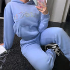 Blaues Sweatshirt-Set mit dekorativen Inschriften, Kapuze und Kängurutasche. Bequemes Freizeitoutfit, ideal für modische Streetwear-Looks.