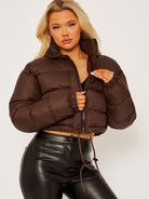 Dunkelbraune Daunenjacke für Damen, modisch und warm, ideal für Herbst und Winter. Perfekt kombinierbar mit Lederhosen für einen trendigen Look.