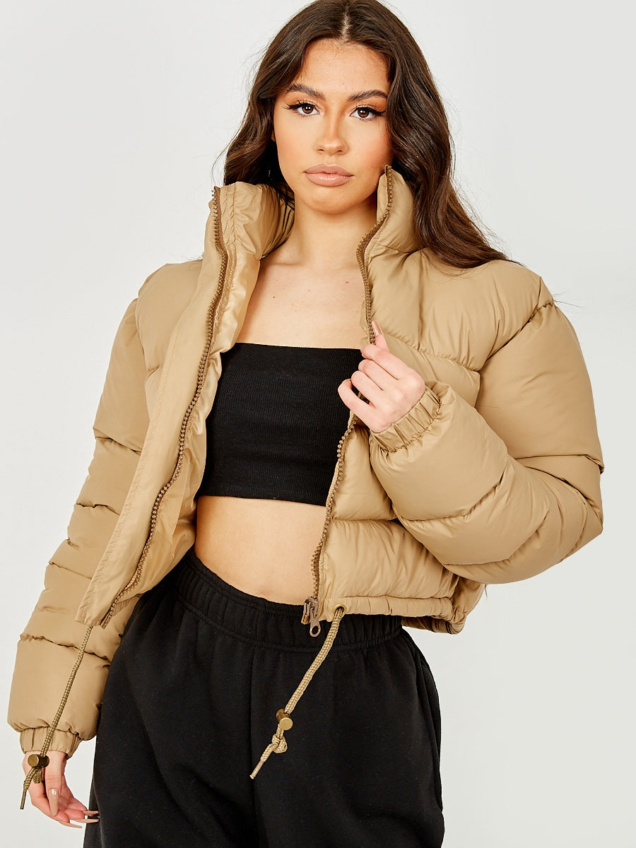 Damen Winterjacke beige, gesteppte Daunenjacke, modisch und warm, ideal für kalte Tage. Perfekt kombinierbar mit schwarzem Top und Hose.