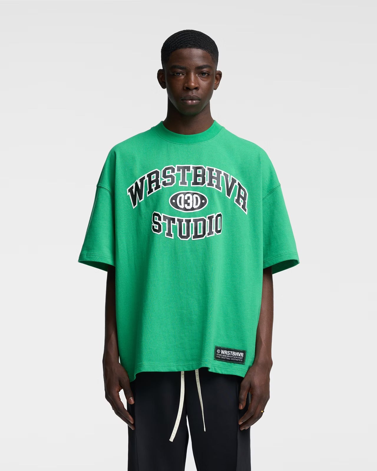 Grünes Oversize-T-Shirt mit "WASTHVR STUDIO"-Aufdruck, lässiger Streetwear-Stil, ideal für trendige Mode und urbanen Look.