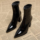 Schwarze Lackleder-Stiefeletten mit spitzer Zehenpartie und Blockabsatz auf Zeitungshintergrund. Modische Damenstiefel, elegant und trendig.