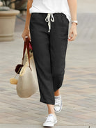 Damenhose in Schwarz, lässig und bequem, mit Kordelzug. Perfekt für Freizeit und Alltag. Kombiniert mit weißen Sneakers und Tasche.