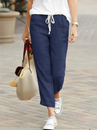 Damenhose in Navyblau aus Leinen, lässig geschnitten mit Kordelzug. Perfekt für Sommermode, kombiniert mit weißen Sneakers und Tasche.