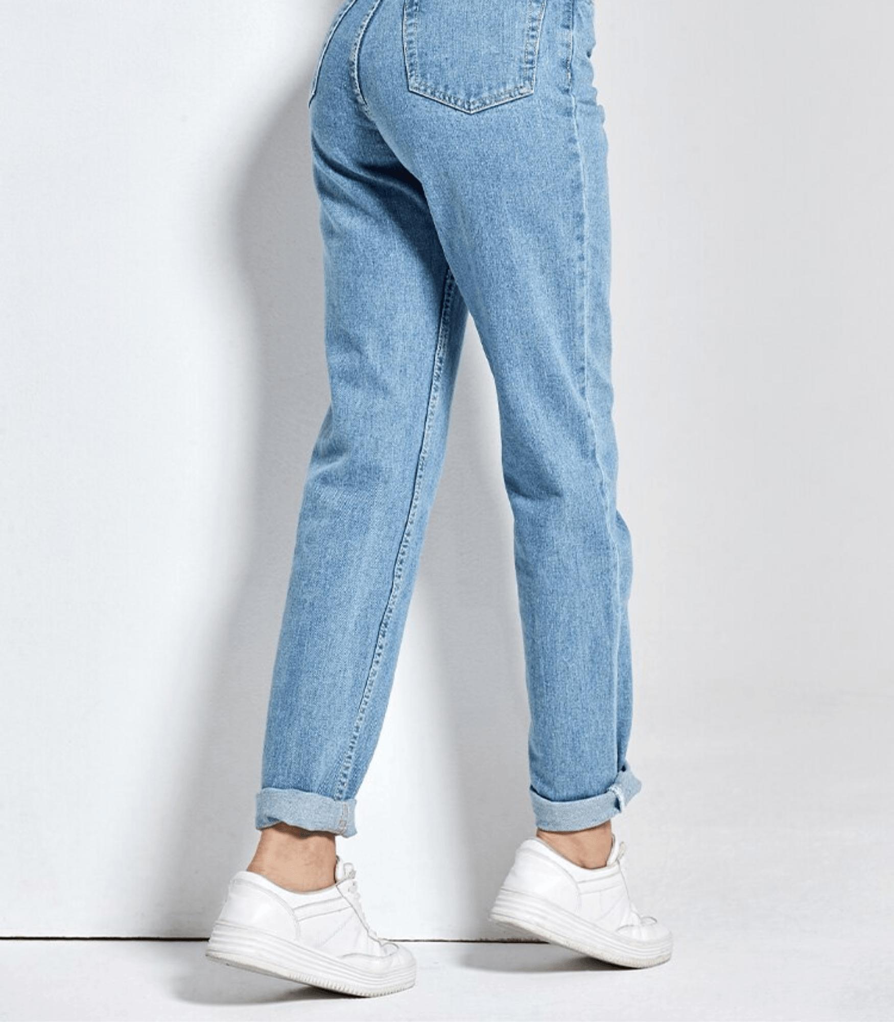Vintage-Jeans mit hoher Taille in hellblauem Denim, kombiniert mit weißen Sneakers. Perfekt für modische Retro-Looks und lässigen Stil.