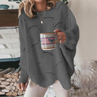 Gestrickter grauer Damenpullover, lässig und bequem, ideal für Herbstmode. Perfekt kombiniert mit einer Tasse Kaffee für gemütliche Stunden.